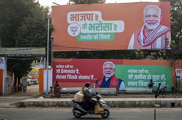 A motorcyclist travels past campaign banners for the BJP featuring PM Modi in Patna, Bihar. - Getty Images