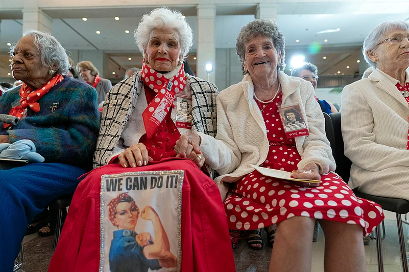 World War II factory workers, known as Rosie the Riveters, Cille MacDonald, left, and Delphine Kaput hold hands during the Congressional Gold Medal Ceremony .