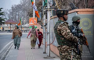 (Photo by Idrees Abbas via Getty Images) : Women walk along a street adorned with Bharatiya Janata Party (BJP) flags and boards, while Indian paramilitary troopers stand alert ahead of Prime Minister Narendra Modi's visit.