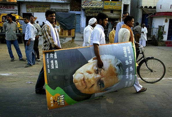 Getty Images : A Bhartiya Janata Party (BJP) supporter carries a picture of Indian Prime Minister and BJP leader Atal Bihari Vajpayee after an election rally in Aligarh, India Thursday, April 29, 2004. Vajpayee and his BJP were ousted from power yesterday in an election upset when the nation's 700 million poor voted against his "India Shining" campaign