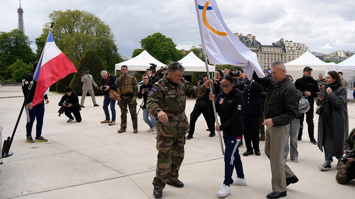 Thibault Camus/AP : A woman holds the Olympic flag at the Invalides monument in Paris on April 24, 2024. The Paris 2024 Olympic Games will run from July 26 to Aug.11 2024.