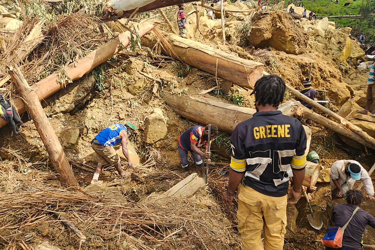 AP : Villagers look for bodies in the debris left behind the landslide.
