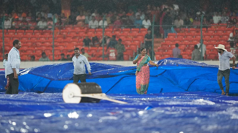 Ground staff cover the pitch as it rains in Hyderabad. AP Photo
