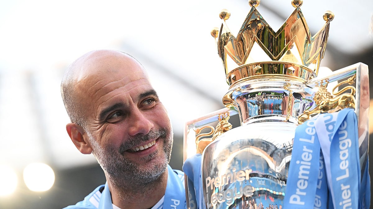 Pep Guardiola poses with the Premier League trophy. - null