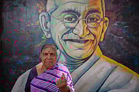 Getty Images : K. S. Gowramma, 65, stands in front of a mural of Indian freedom fighter Mohandas Karamchand Gandhi and shows her finger marked with indelible ink after voting in the second phase of the general elections on April 26, 2024 in Bengaluru, India.