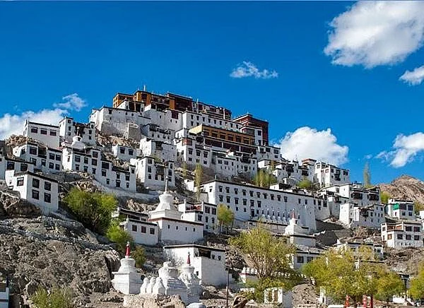 Thikse Monastery, a serene white structure nestled on a picturesque hillside.