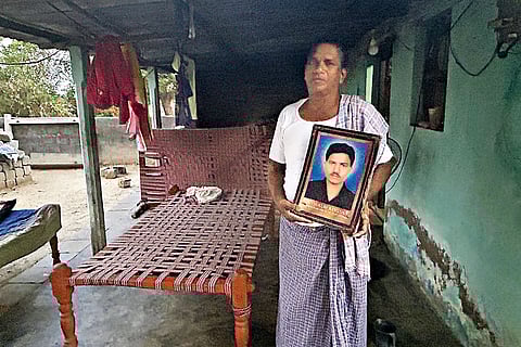 Guthpuri Bokaiah holds up a photo of his son who died by suicide in Saudi Arabia