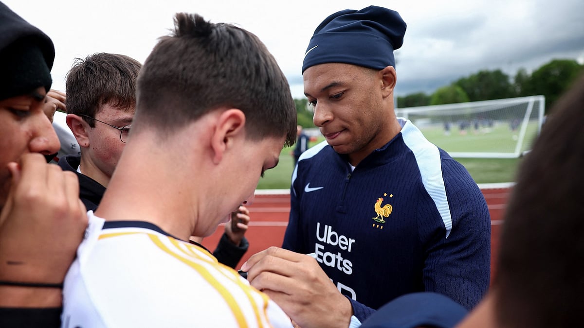 Kylian Mbappe signs a fan's Real Madrid shirt at a France training session. - null