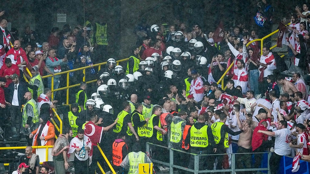 AP/Andreea Alexandru : Riot police separate Turkish and Georgian fans after they briefly scuffled ahead of a Group F match between Turkey and Georgia at the Euro 2024 soccer tournament in Dortmund, Germany, Tuesday, June 18, 2024.