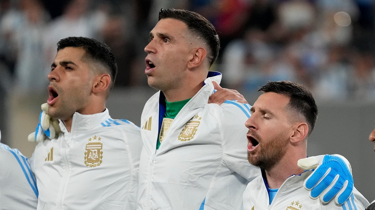 Argentinas Lionel Messi, right, and Cristian Romero flank goalkeeper Emiliano Martinez singing the national anthem. AP Photo