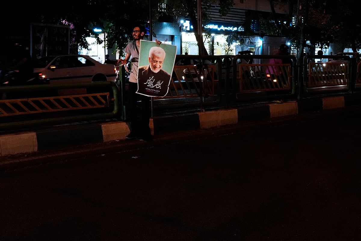 AP : A supporter of Saeed Jalili, a candidate for the June 28, presidential election, holds his poster during a campaign gathering in Tehran, Iran, Wednesday, June 26, 2024.