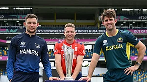 Photo: X/ @ICC : Namibia skipper Gerhard Erasmus (L) with England and Australia captain and the ICC T20 World Cup 2024 trophy.