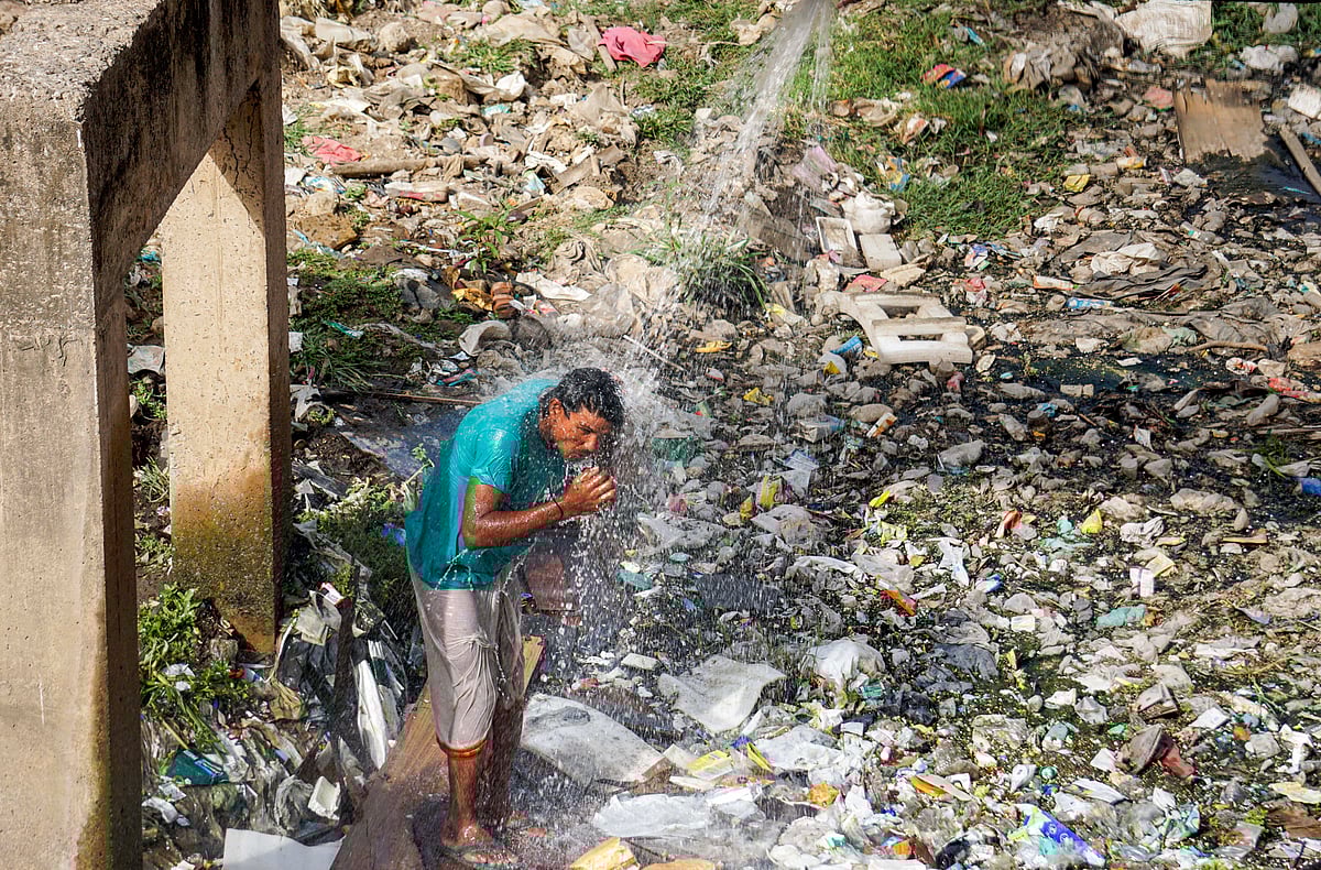 PTI : A man bathes with water leaking from a pipeline at Nizamuddin area on a hot summer day, in New Delhi