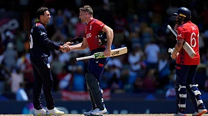AP Photo/Ricardo Mazalan : United States' Shadley Van Schalkwyk, left, greets England's captain Jos Buttler at the end of the ICC Men's T20 World Cup cricket match between the United States and England at Kensington Oval in Bridgetown, Barbados, Sunday, June 23, 2024.
