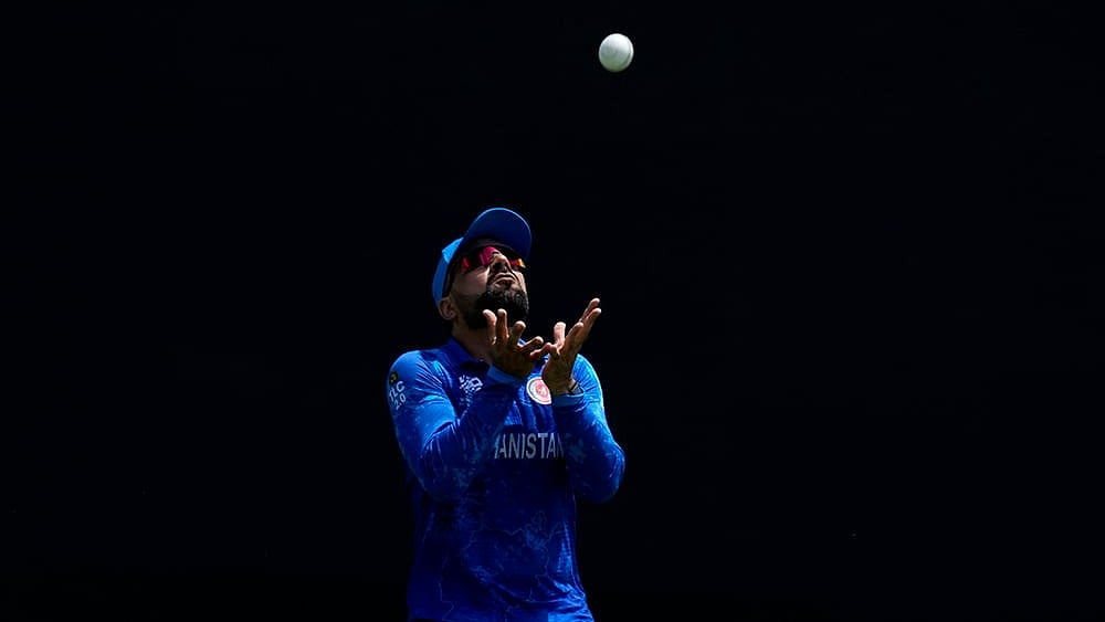 | Photo: AP/Ricardo Mazalan : Rashid Khan prepares to take o dismiss India's captain Rohit Sharma 