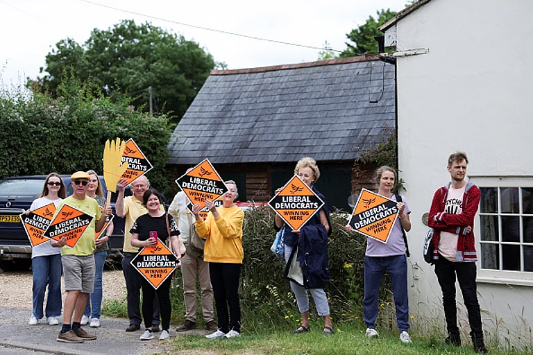People hold Liberal Democrat signs outside Braishfield primary school as British Prime Minister and Conservative Party leader Rishi Sunak makes a visit as part of a Conservative general election campaign event in Romsey, Hampshire, southern England on July 3, 2024.  - Getty Images