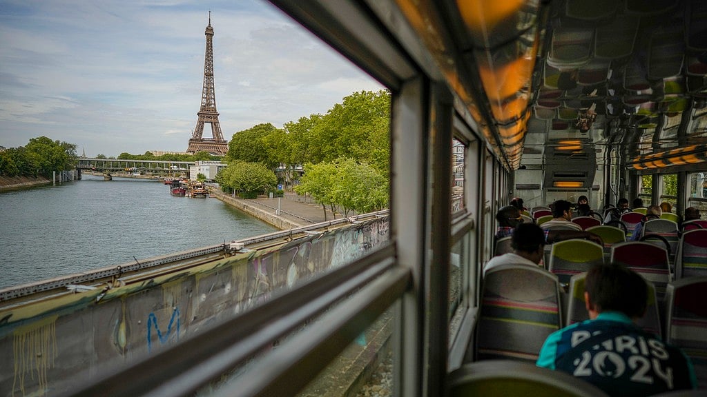 AP/Andrew Medichini : The Eiffel Tower is seen through the window of a commuter train ahead of the 2024 Paris Olympics.