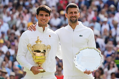 Carlos Alcaraz, left, of Spain holds his trophy after defeating Novak Djokovic, right, of Serbia in the men's singles final at the Wimbledon tennis championships in London, Sunday, July 14, 2024.