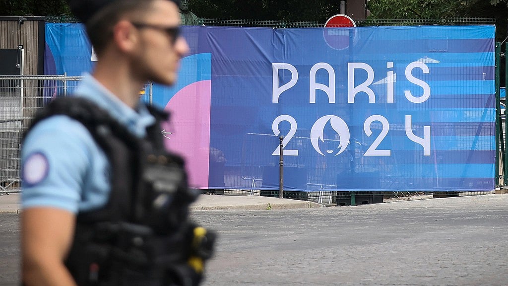 AP/Thomas Padilla : A police officer walks past a Paris olympics canvas at the 2024 Summer Olympics, Saturday, July 20, 2024, in Paris, France.
