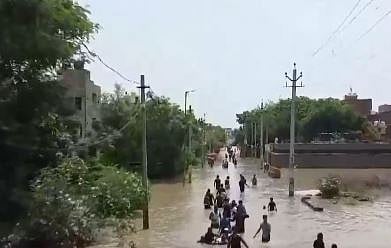 X/ Screengrab from video poste by ANI : Localites  wading through water in Bawana's JJ Colony after Munak canal breach in Delhi |