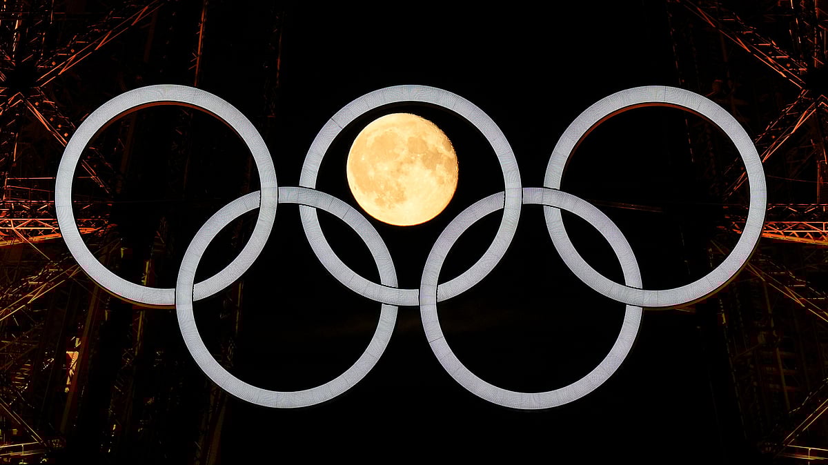  (AP Photo/David J. Phillip) : A full moon rises behind the Olympic rings hanging from the Eiffel Tower Monday, July 22, 2024, in Paris, France. The opening ceremony for the Olympic Games is Friday.