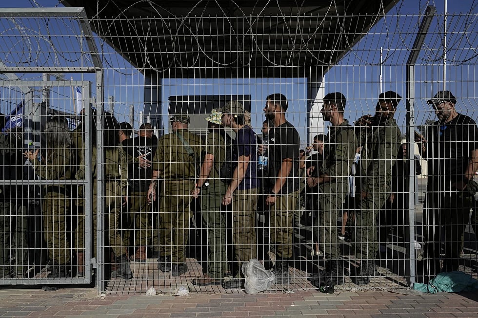 Israeli soldiers gather at the gate to the Sde Teiman military base, as people hold protests |
