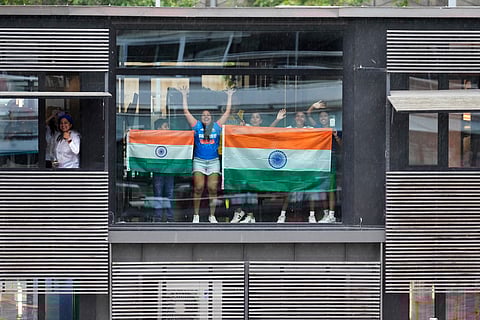 Indians cheer from a building as their athletes travel in a boat on the Seine River in Paris, France, during the opening ceremony of the 2024 Summer Olympics, Friday, July 26, 2024.