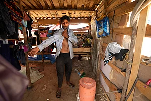 AP Photo : Aamir Shekh puts on a shirt before heading out in a heat wave to a garbage dump on the outskirts of Jammu,