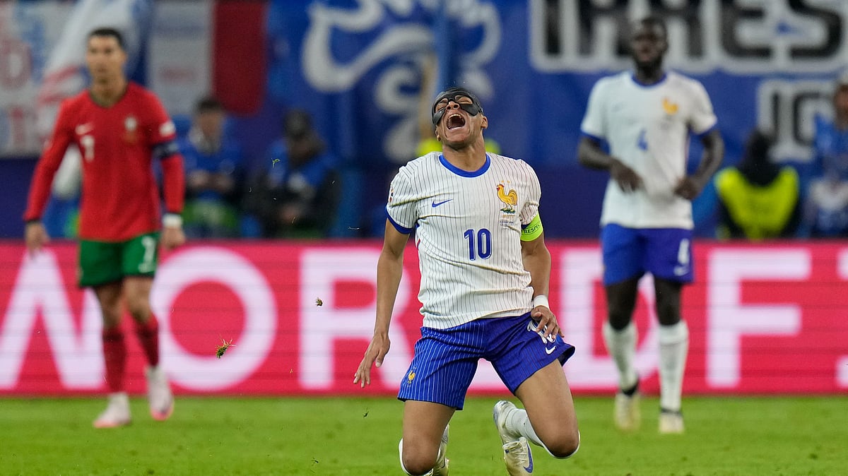 AP Photo/Hassan Ammar : Kylian Mbappe of France, centre, falls after a collision with Portugal's Joao Palhinha during a quarter-final match at the Euro 2024 tournament in Hamburg, Germany.