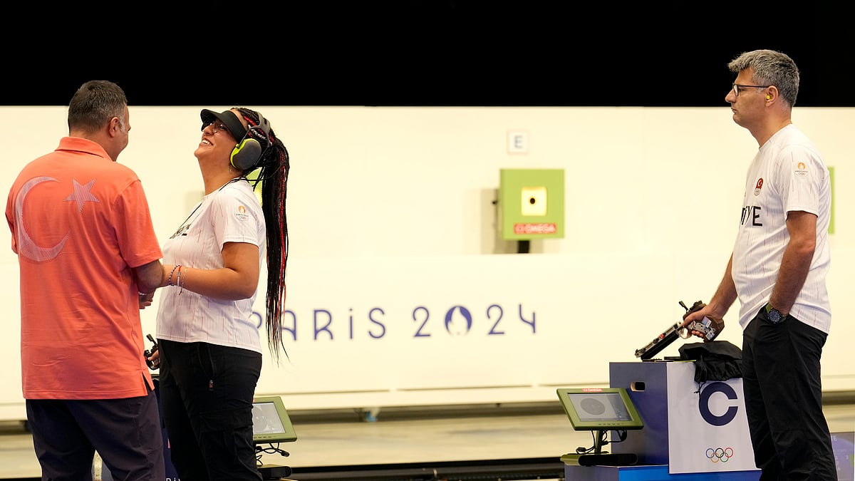 AP Photo/Manish Swarup : Turkish shooter Yusuf Dikec, right, looks on as Turkey's coach talks to Dikec's teammate Sevval Ilayda Tarhan during a time-out break at the 10m air pistol mixed team final, in Chateauroux, France, at the 2024 Summer Olympics.