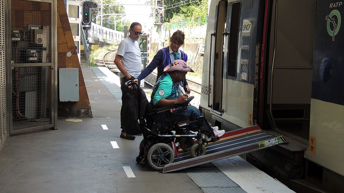  AP Photo/Tom Nouvian : Ndieme Lame, a 57-year-old volunteer for the Paris 2024 Olympic and Paralympic Games navigates a ramp to join a RER train with the help of rail agents, during the 2024 Summer Olympics, Wednesday, Aug. 7 2024, in Paris, France.
