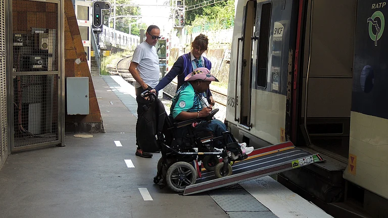 Ndieme Lame, a 57-year-old volunteer for the Paris 2024 Olympic and Paralympic Games navigates a ramp to join a RER train with the help of rail agents, during the 2024 Summer Olympics, Wednesday, Aug. 7 2024, in Paris, France. - AP Photo/Tom Nouvian