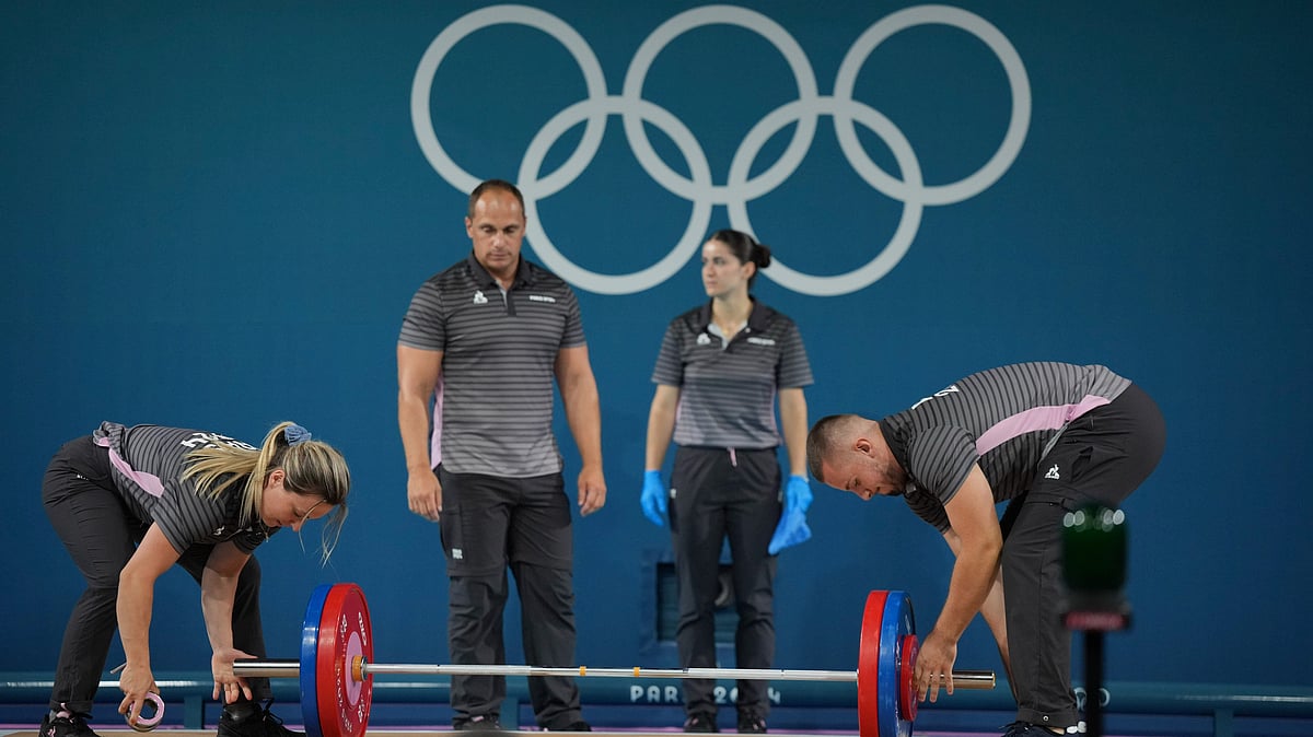  AP Photo/Kin Cheung : Loaders set the weight on the bar during the women's 59kg weightlifting event at the 2024 Summer Olympics, Thursday, Aug. 8, 2024, in Paris, France.
