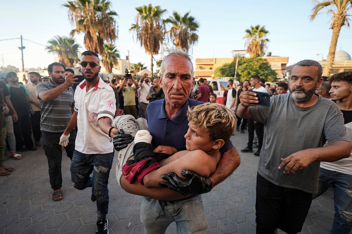 (AP Photo/Abdel Kareem Hana) : A Palestinian man carries an injured child after an Israeli airstrike in Deir al Balah, Gaza Strip, Tuesday, Aug. 6, 2024. 