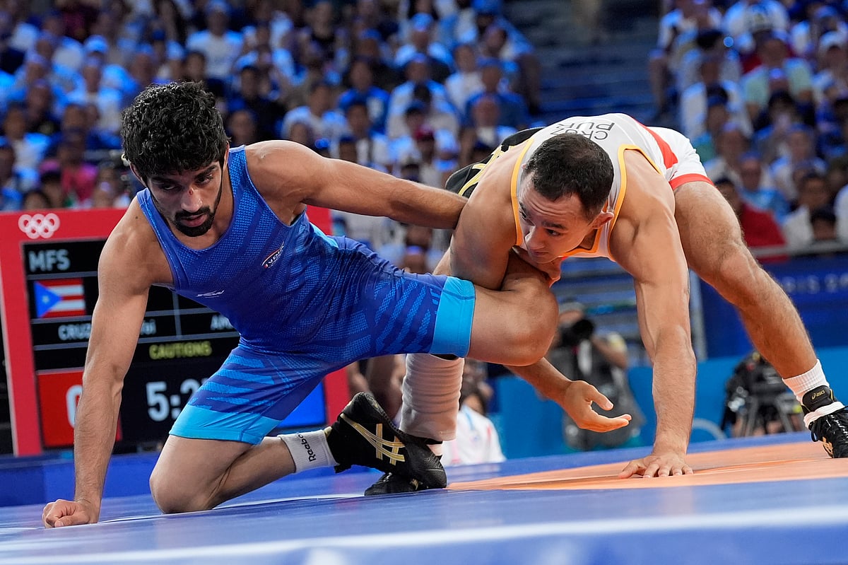  (AP Photo/Eugene Hoshiko) : Puerto Rico's Darian Tai Cruz and India's Aman Aman, in blue, compete in their men's freestyle 57kg bronze medal wrestling match, at Champ-de-Mars Arena, during the 2024 Summer Olympics, Friday, Aug. 9, 2024, in Paris, France.