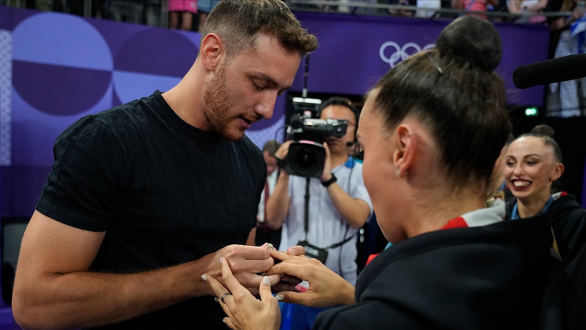 AP Photo/Dar Yasin : Massimo Bertelloni, left, puts a ring on the finger of team Italy's Alessia Maurelli after she accepted his marriage proposal at the end of the group all-around rhythmic gymnastics final at La Chapelle Arena during the 2024 Summer Olympics.