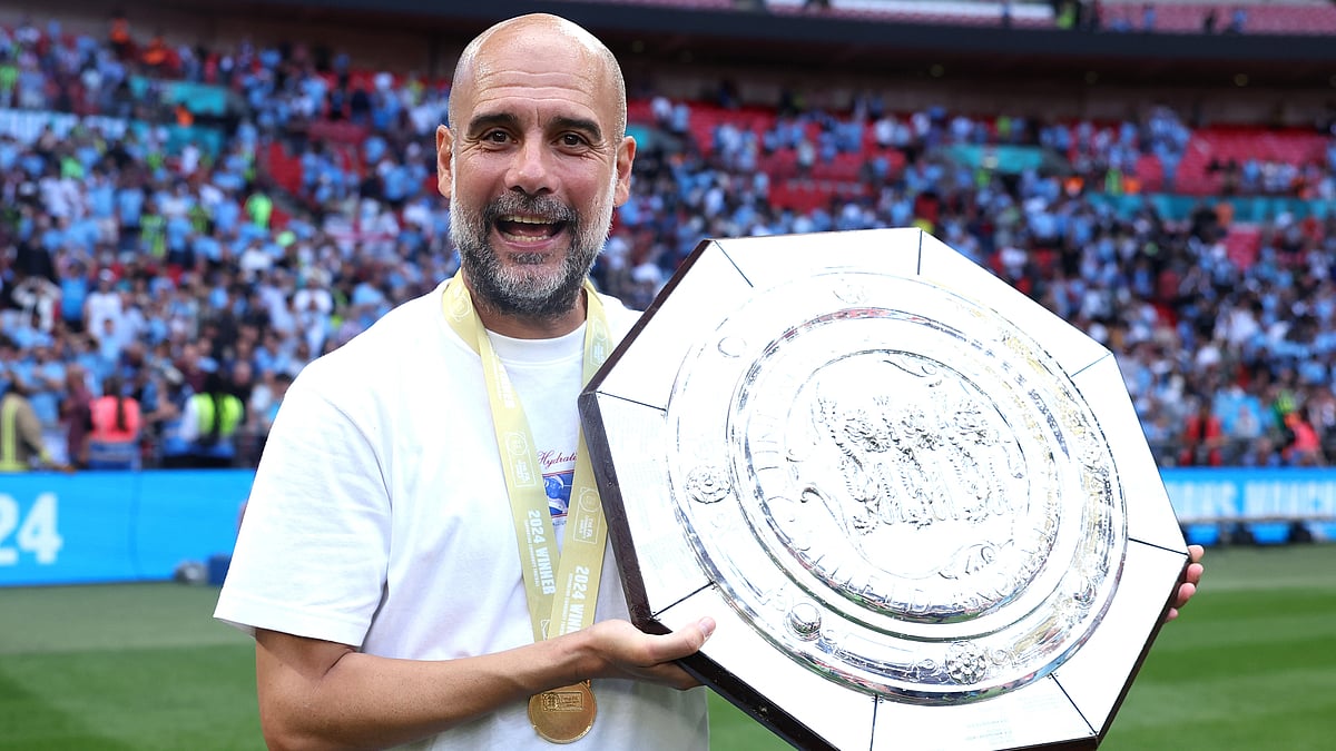 Pep Guardiola holds the Community Shield after Saturday's win. - null