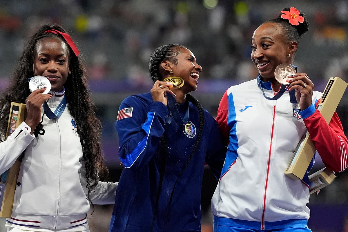 (AP Photo/Matthias Schrader) : Women's 100-meter hurdles gold medalist Masai Russell, centre, of the United States, stands with silver medalist Cyrena Samba-Mayela, left, of France, and bronze medalist Jasmine Camacho-Quinn, of Puerto Rico, on the podium at the 2024 Summer Olympics, Saturday, Aug. 10, 2024, in Saint-Denis, France. 