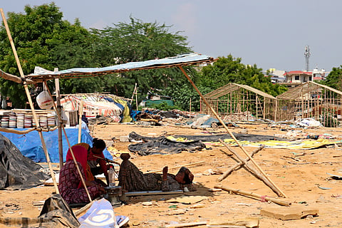 Women rest under a temporary structure at the demolished site