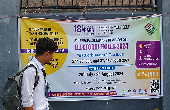 A student is looking at the Election banner as he is walking along a road in Srinagar