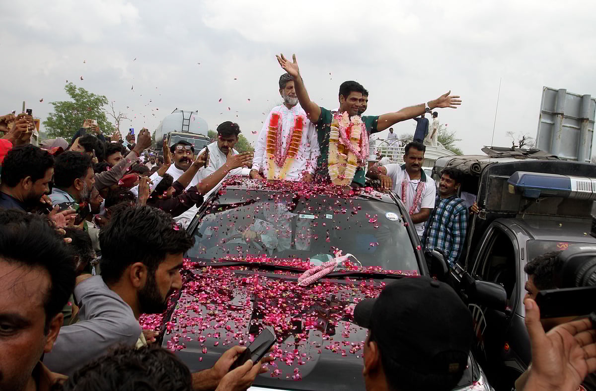 (AP Photo/Asim Tanveer) : Men's javelin gold medalist, Arshad Nadeem of Pakistan, centre, waves to people outside his village in Mian Channu, Khanewal district, of Pakistan, Sunday, Aug. 11, 2024. 


