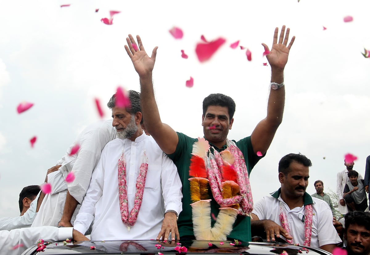 (AP Photo/Asim Tanveer) : Men's javelin gold medalist, Arshad Nadeem of Pakistan, centre, waves to people outside his village in Mian Channu, Khanewal district, of Pakistan, Sunday, Aug. 11, 2024. 


