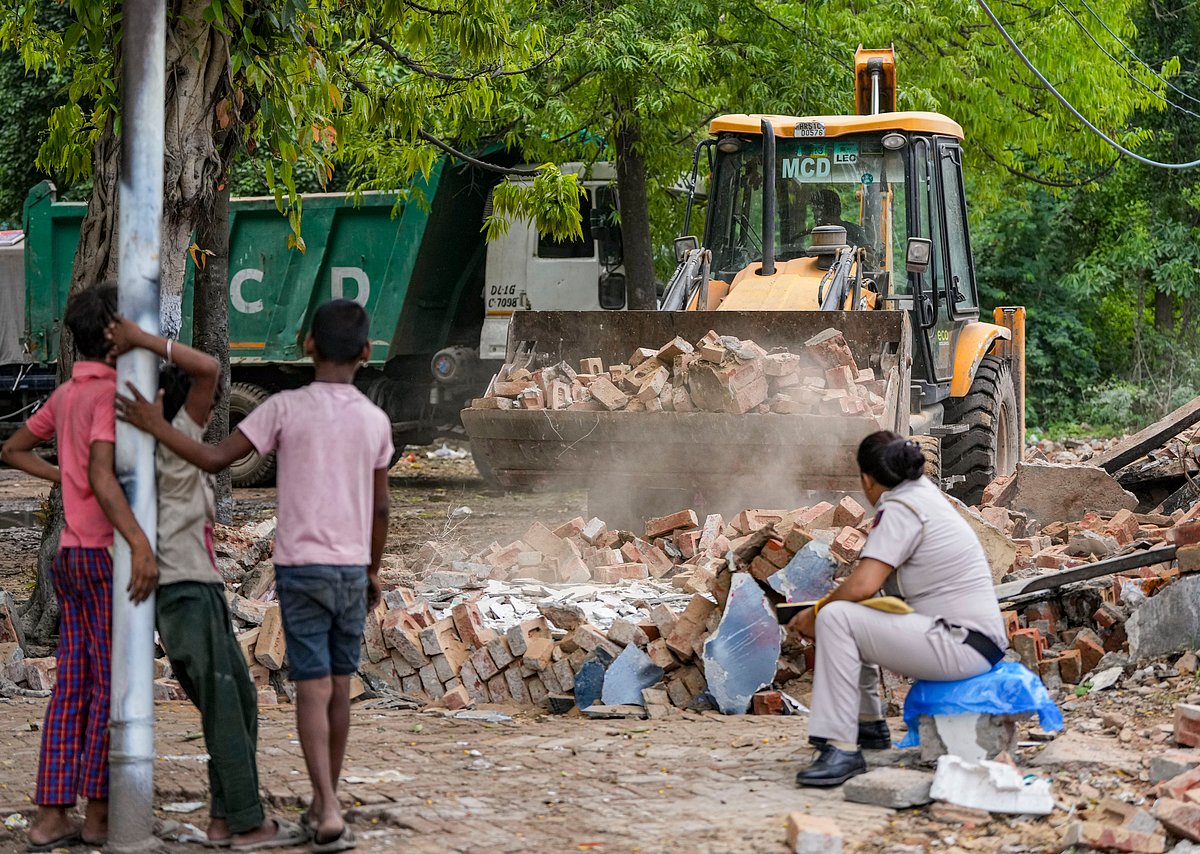 Children watch as bulldozer clears rubble during a demolition drive in Delhi. 
Credits