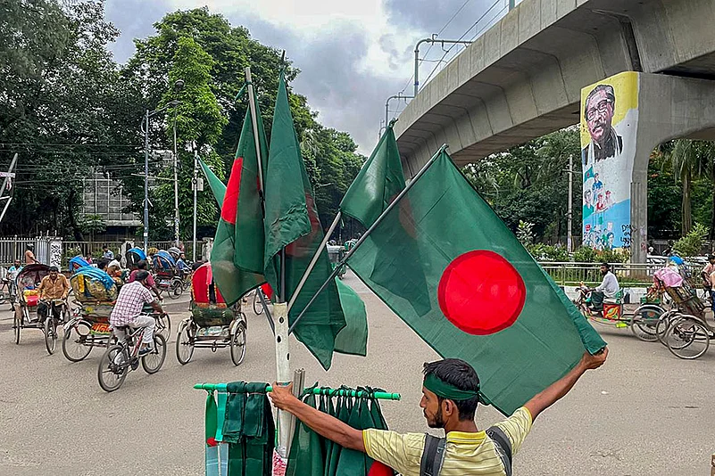 A flag-seller stands on the periphery of a memorial site near Dhaka University