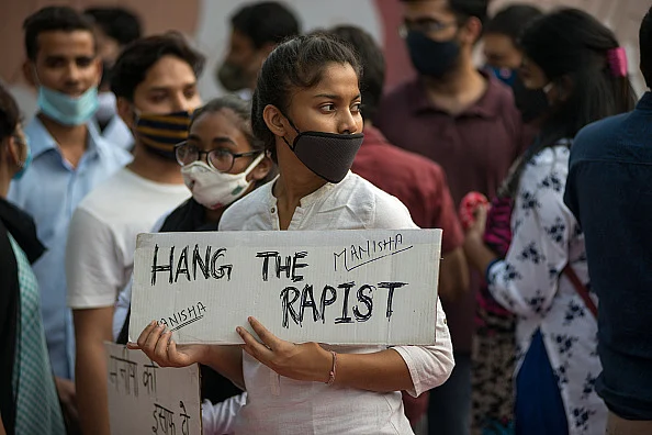Young College girl holding a placard saying, hang the rapist