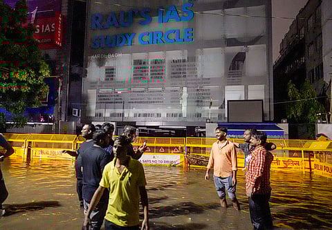 Students stand amid waterlogging in front of Rau's IAS Study Circle at Old Rajinder Nagar, in New Delhi, Wednesday, July 31, 2024