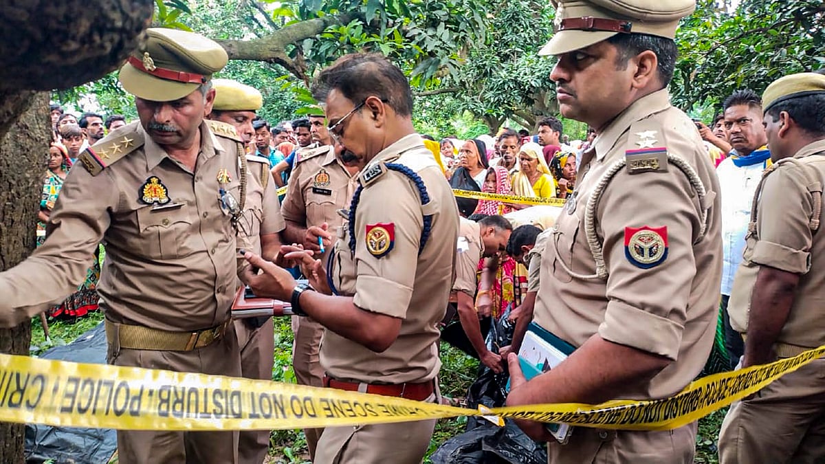 PTI Photo : Police personnel investigate after the bodies of two girls were found hanging from a tree, at Kayamganj area in Farrukhabad