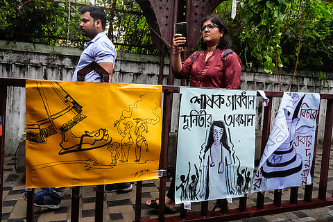 Kolkata rape-murder case: Onlookers walk past posters of an ongoing protest rally by the Junior Doctors in Kolkata