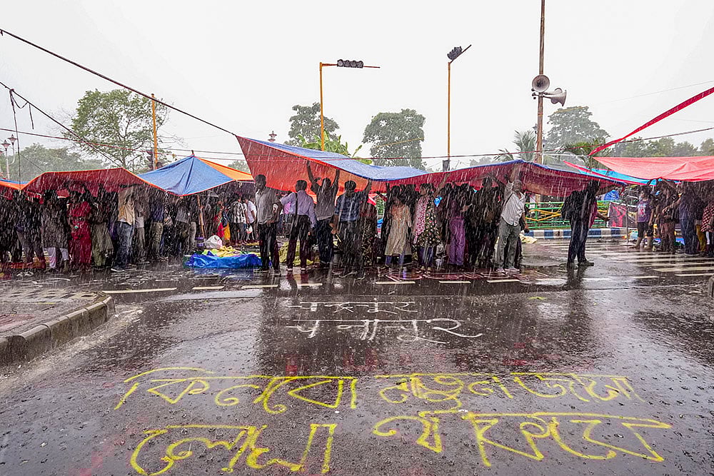 | Photo: PTI/Swapan Mahapatra : Kolkata rape-murder case: Agitators take cover during rains