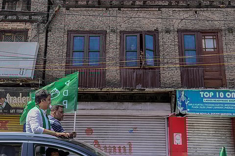 J&K Assembly Polls: People watch from a window of their old house during a road show